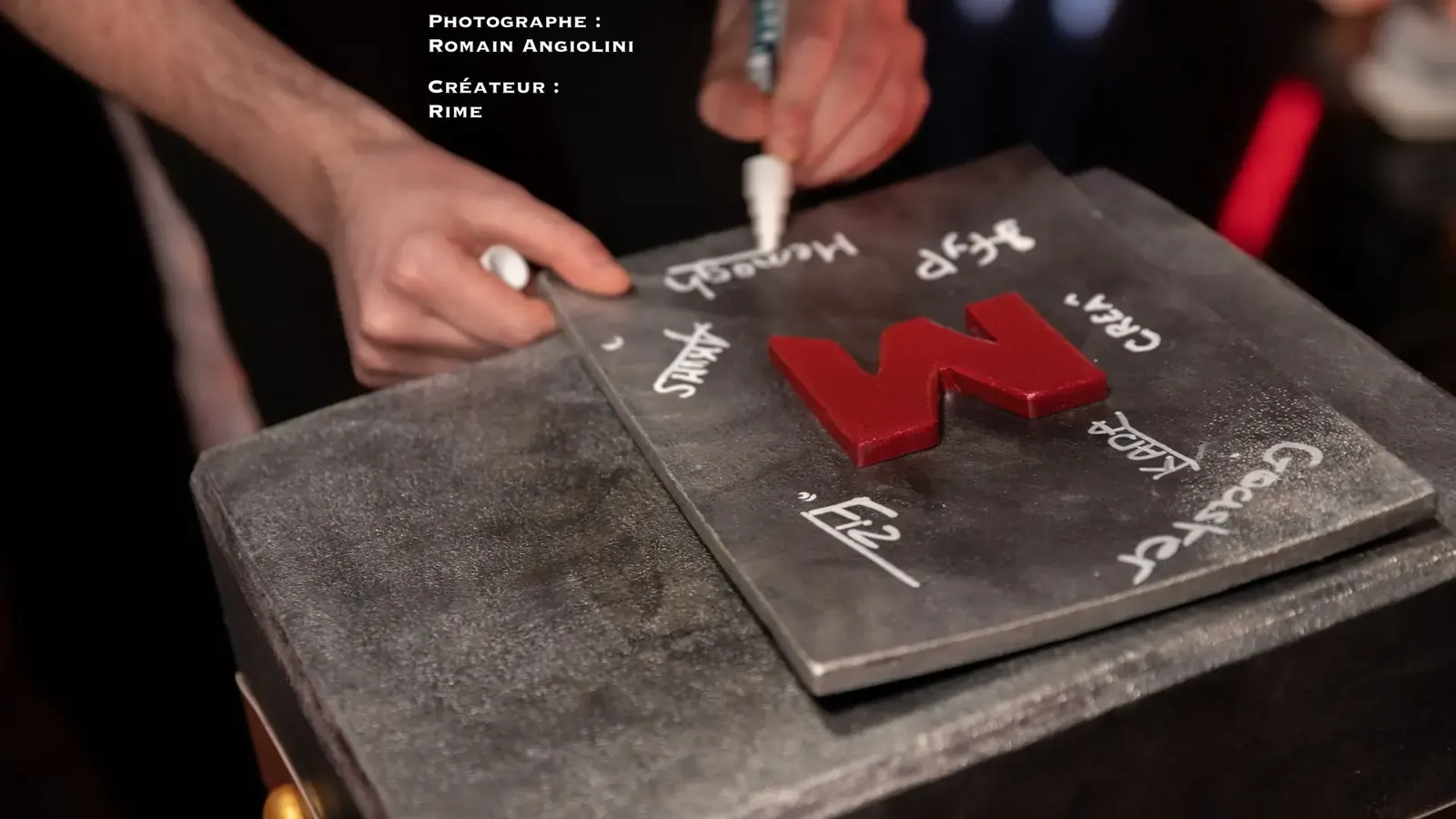 Marteau artisanal en forme de M rouge, entouré de dédicaces des joueurs Mandatory